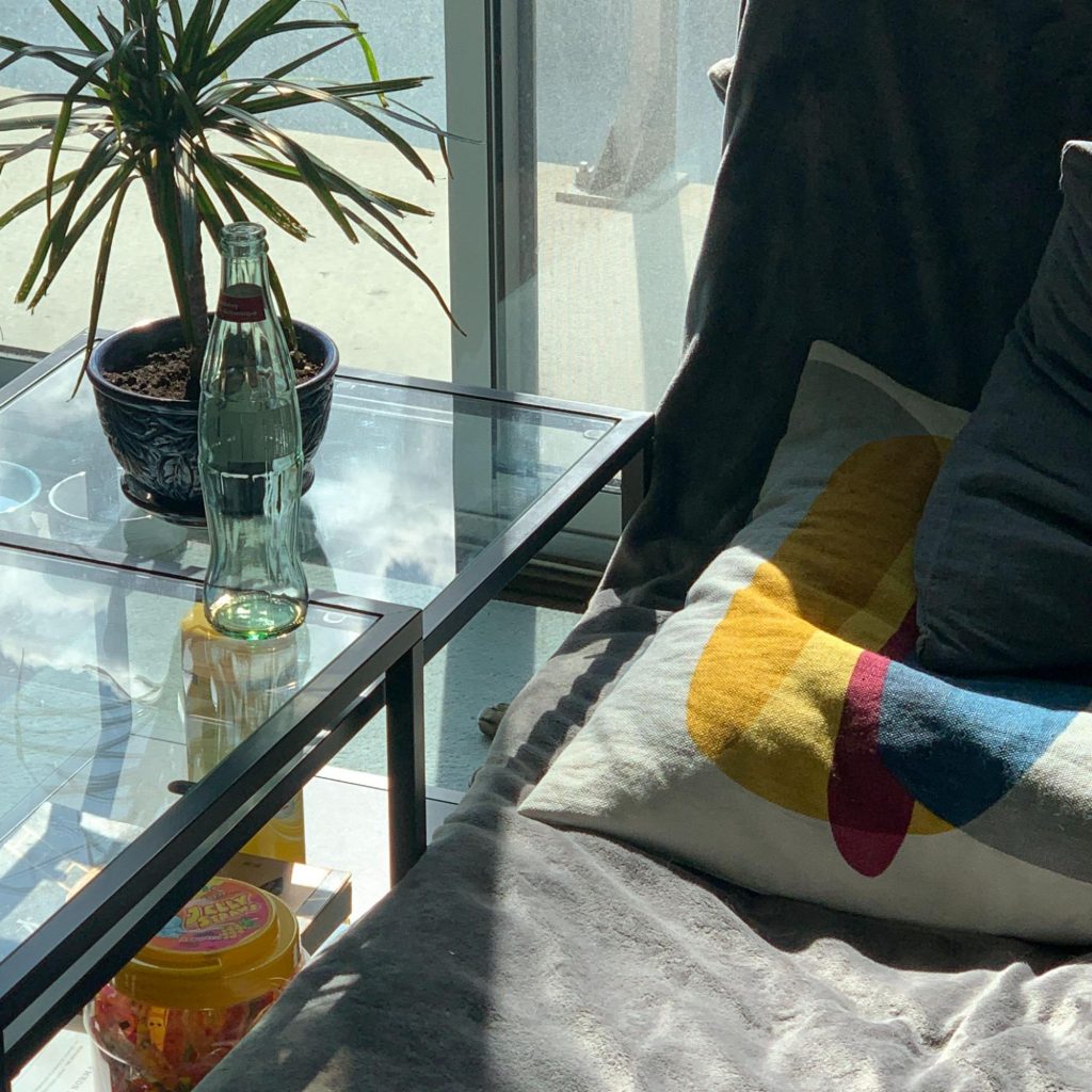 Bed side table with empty glass bottle and plant